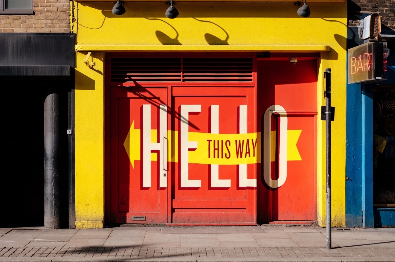 Hello this way printed on a red metal gate